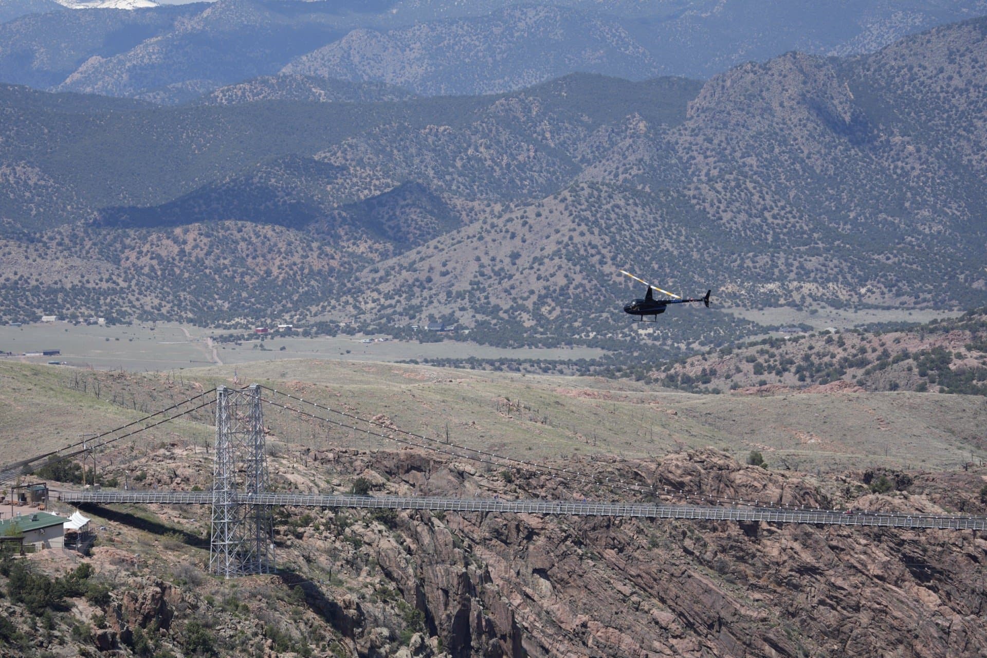 Robinson R44 helicopter flying over Royal Gorge canyon with 1,200-foot granite walls and Colorado mountain backdrop - Epic Adventures tour