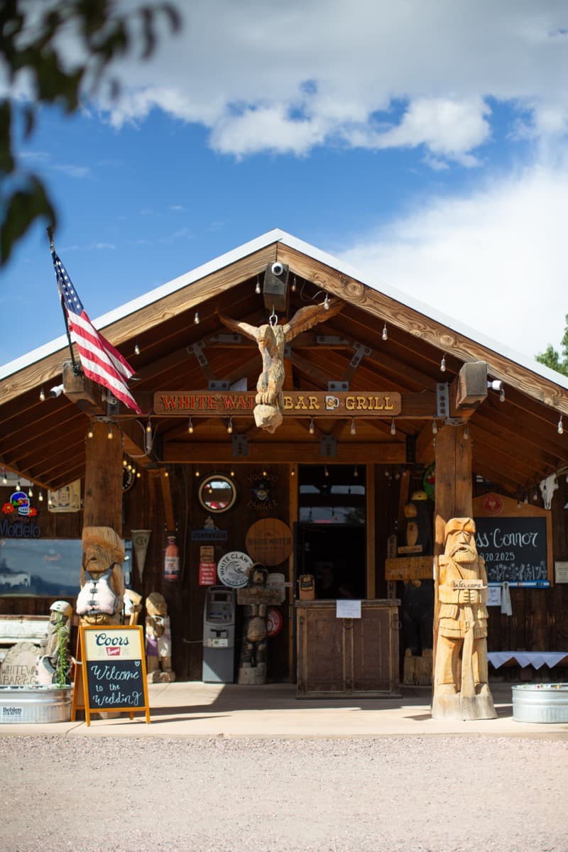 WhiteWater Bar & Grill venue exterior with rustic log cabin entrance, carved totem figures, and antler decor