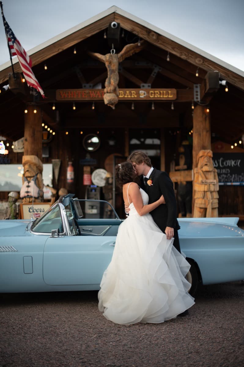 Newlywed couple with vintage Thunderbird at WhiteWater Bar & Grill at golden hour dusk